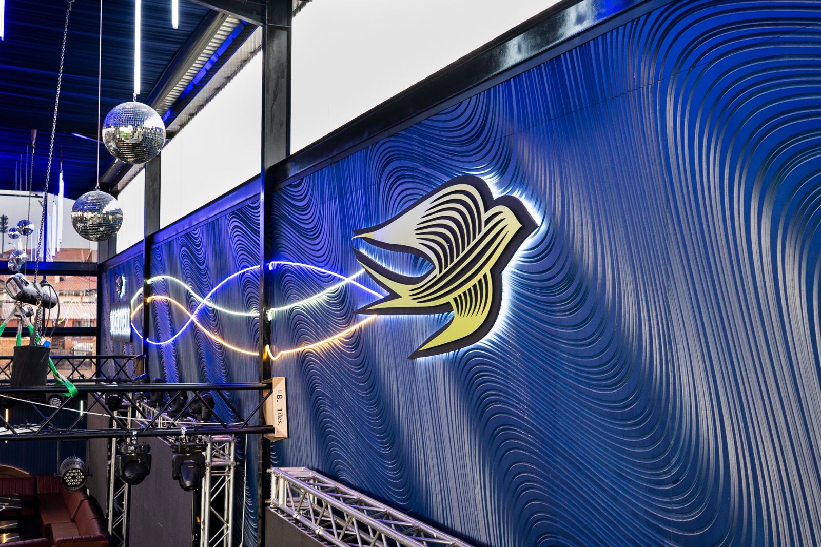 Backlit swallow and neon on the CNC wave wall